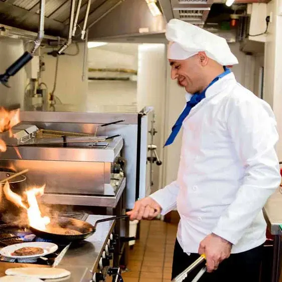 [[community_name]] Chef Created Meals, chef frying a dish.