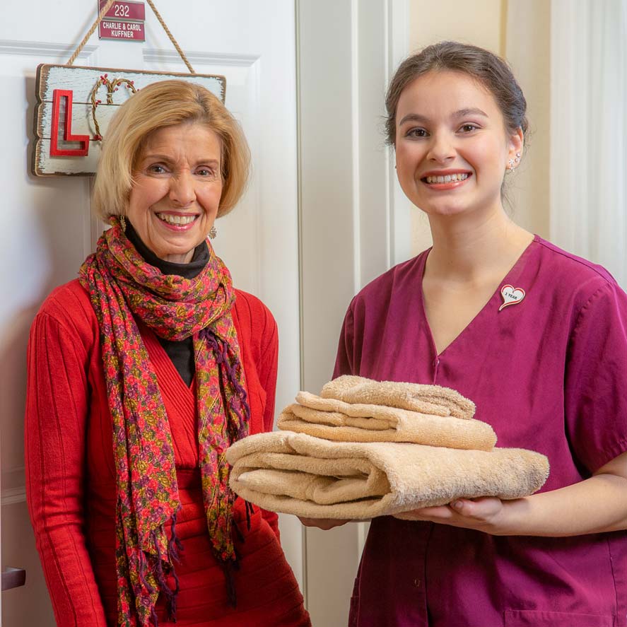 A team member delivering fresh linens to a resident at Somerset Lodge